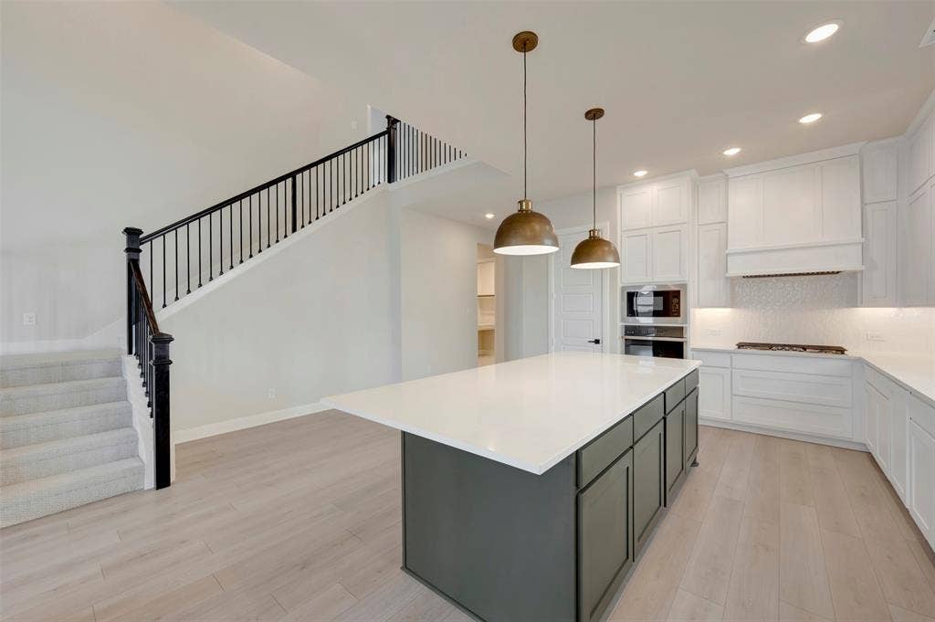 3752 Bermuda Grass Way, Grand Prairie, TX 76084 Two tone kitchen featuring two tone cabinets, backsplash, a kitchen island, light wood-style flooring, and hanging light fixtures