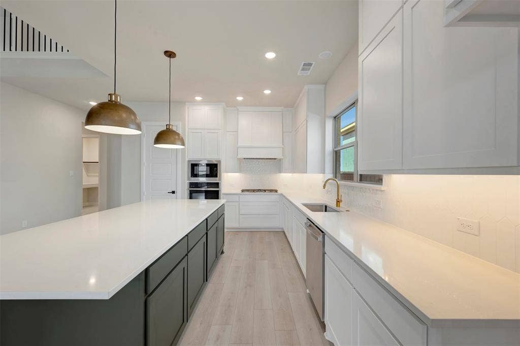3752 Bermuda Grass Way, Grand Prairie, TX 76084 Kitchen featuring two tone cabinets, tasteful backsplash, light wood finished floors, hanging light fixtures, and light stone counters