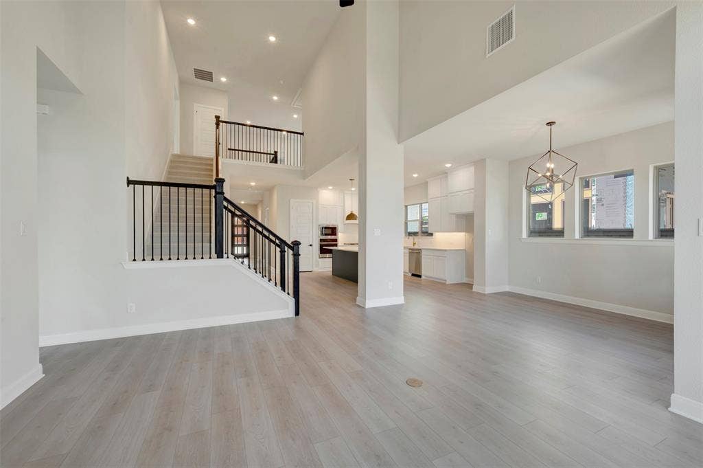 3752 Bermuda Grass Way, Grand Prairie, TX 76084 Unfurnished living room with a chandelier, a high ceiling, and light wood-style floors
