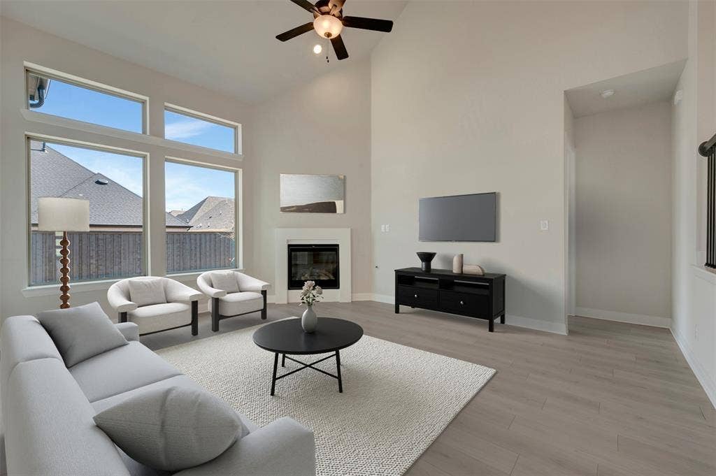 3752 Bermuda Grass Way, Grand Prairie, TX 76084 Living room featuring a glass covered fireplace, light wood finished floors, a ceiling fan, and lofted ceiling