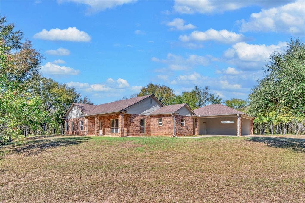 556 Wildwood Trail, Lorena, TX 76655 Ranch-style home featuring a front yard, brick siding, an attached garage, roof with shingles, and a porch