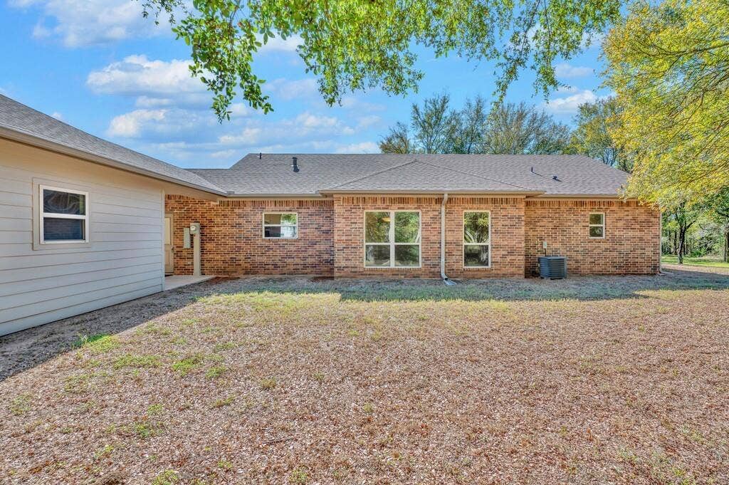 556 Wildwood Trail, Lorena, TX 76655 Rear view of property with a patio area, a shingled roof, brick siding, and a lawn