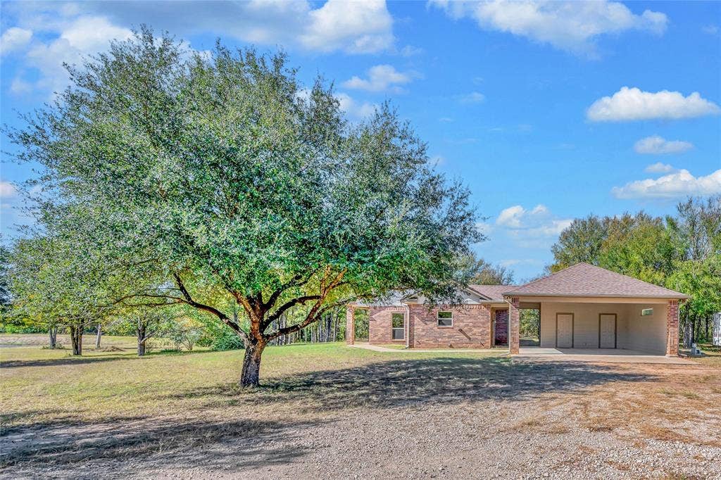 556 Wildwood Trail, Lorena, TX 76655 View of front facade featuring a front lawn, driveway, a shingled roof, brick siding, and a carport