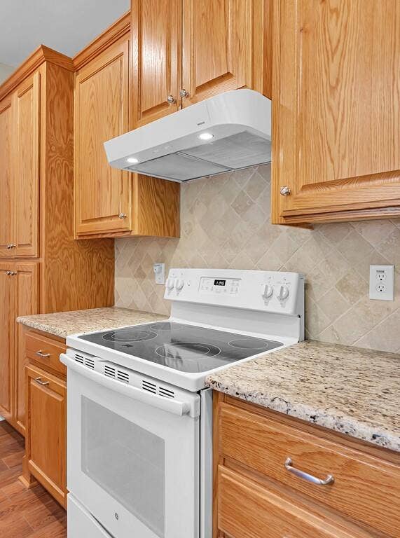 556 Wildwood Trail, Lorena, TX 76655 Kitchen with white electric range oven, range hood, backsplash, and light stone counters