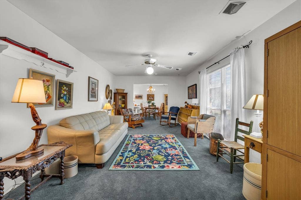Living room with dark colored carpet, a ceiling fan, and a chandelier