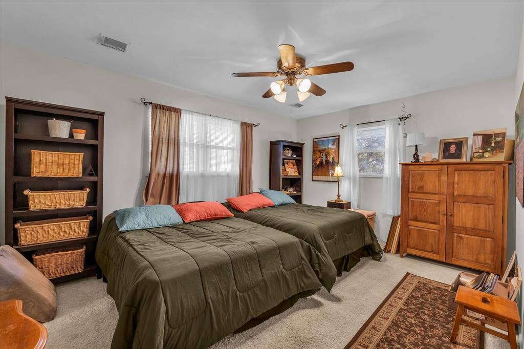 Carpeted bedroom with multiple windows and a ceiling fan
