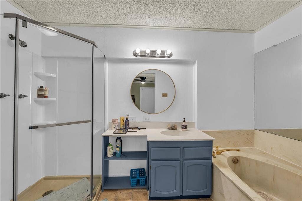 Full bathroom with vanity, a shower stall, a garden tub, a textured ceiling, and light tile patterned flooring