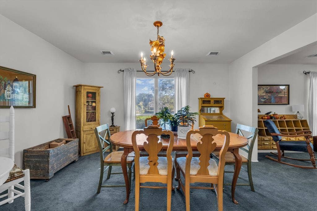 Dining room with dark colored carpet and a chandelier
