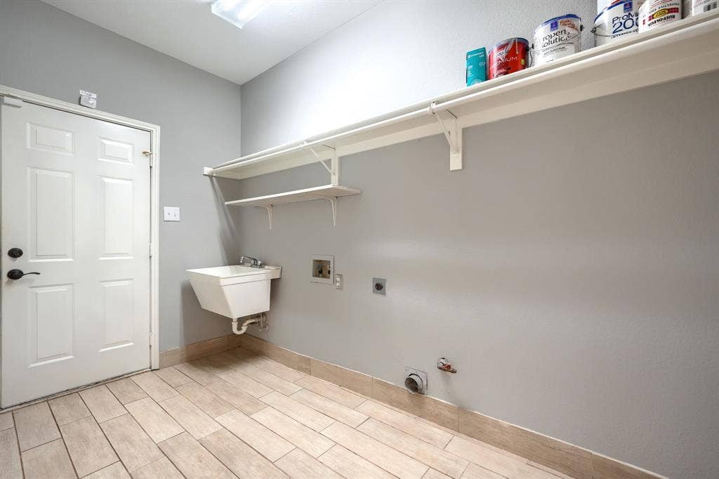 2309 York Court, Carrollton, TX 75006 Utility room featuring wood-finish tile flooring, a wall-mounted utility sink, and built-in shelving