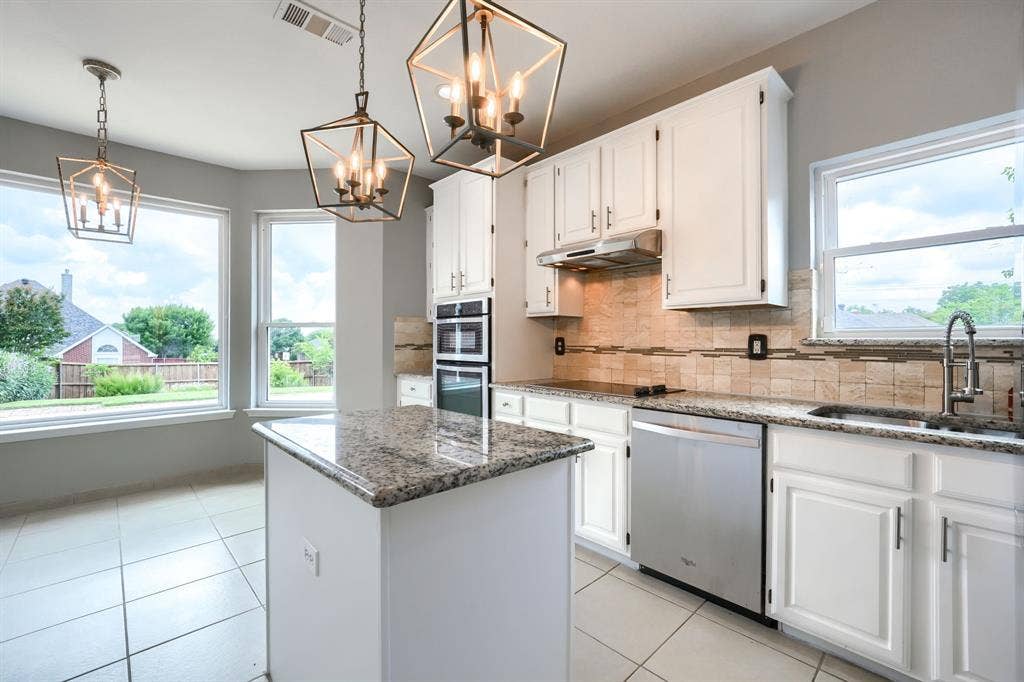 2309 York Court, Carrollton, TX 75006 Kitchen featuring a central island with a granite countertop, white cabinetry, and stainless steel appliances