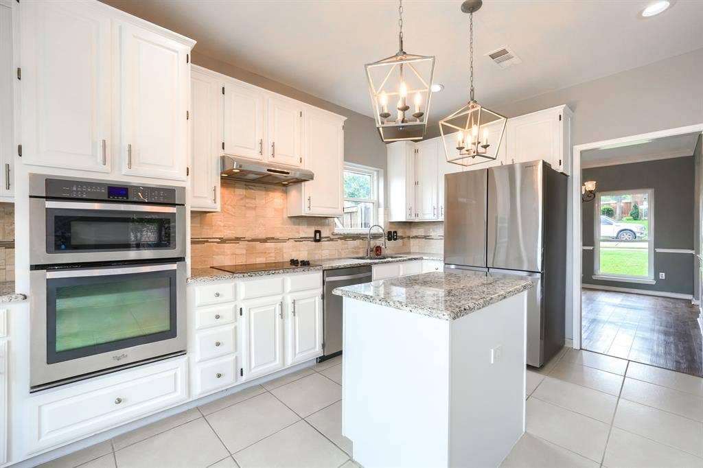 2309 York Court, Carrollton, TX 75006 Kitchen featuring white cabinetry, stainless steel appliances, granite countertops, and an island
