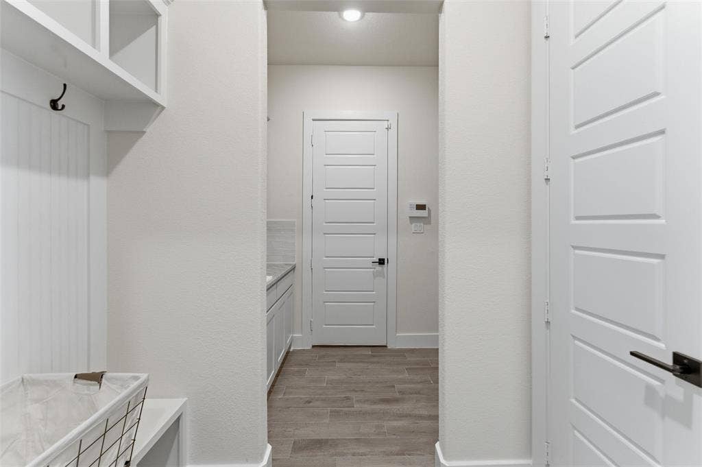 Entryway mudroom area featuring built-in shelving, coat hooks, and a bench