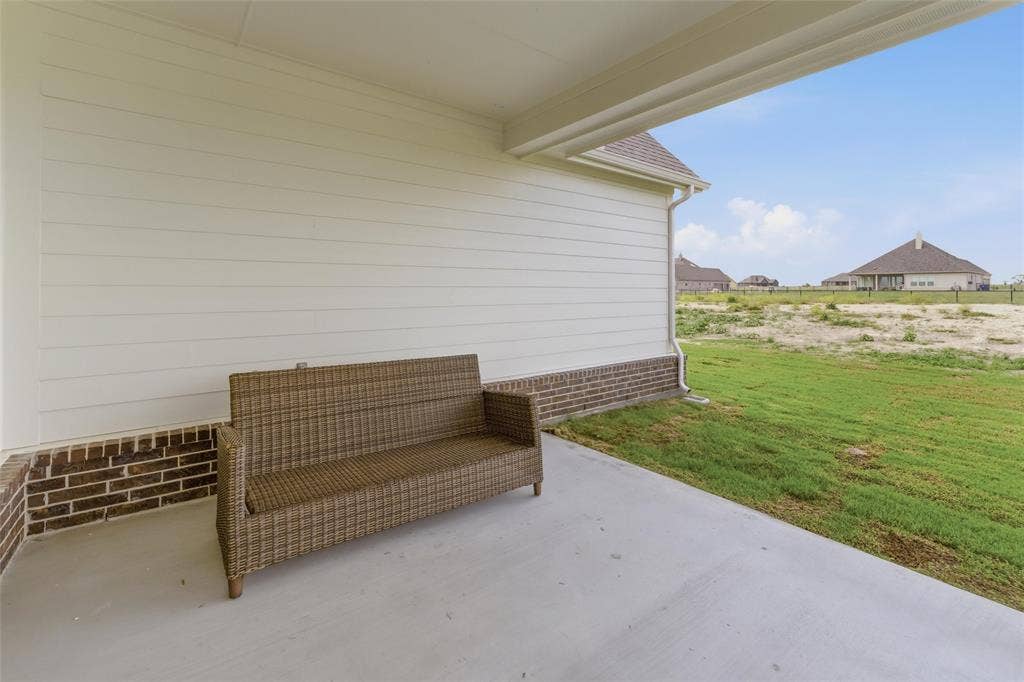 Covered patio with a concrete surface, featuring brick detailing and horizontal siding