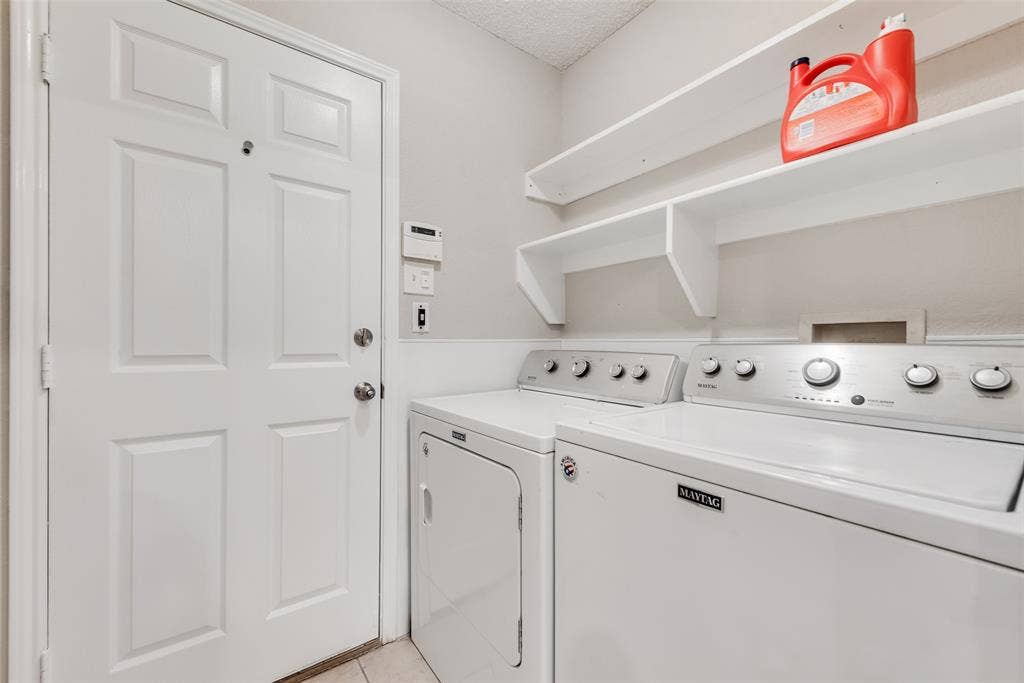 617 Madeline Court, Azle, TX 76020 Washroom featuring washing machine and clothes dryer, a textured ceiling, and light tile patterned flooring