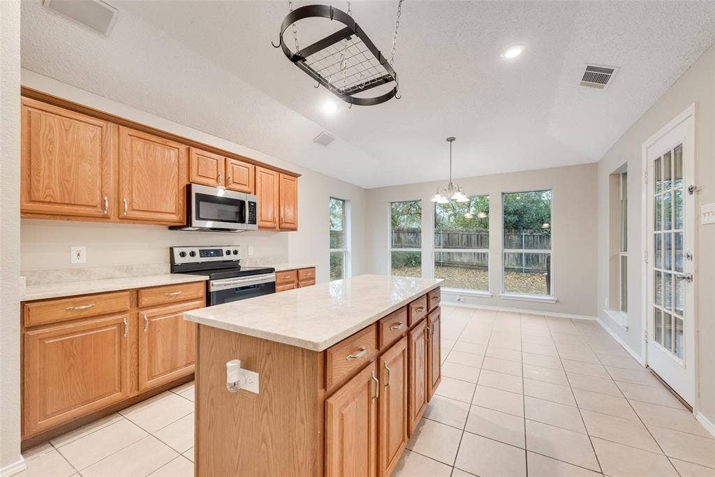 617 Madeline Court, Azle, TX 76020 Kitchen featuring stainless steel appliances, pendant lighting, light tile patterned floors, a chandelier, and a kitchen island