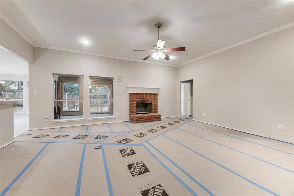 617 Madeline Court, Azle, TX 76020 Unfurnished living room with a brick fireplace, ceiling fan, and ornamental molding