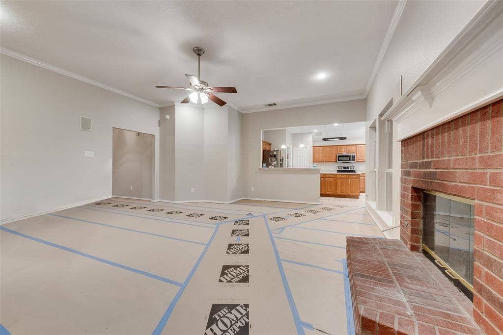 617 Madeline Court, Azle, TX 76020 Unfurnished living room featuring crown molding, a ceiling fan, and a fireplace