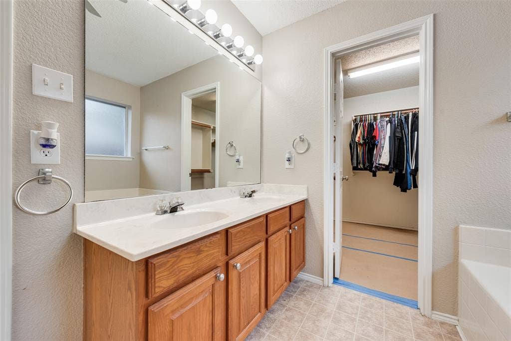 617 Madeline Court, Azle, TX 76020 Full bathroom with a textured wall, a garden tub, double vanity, and a walk in closet