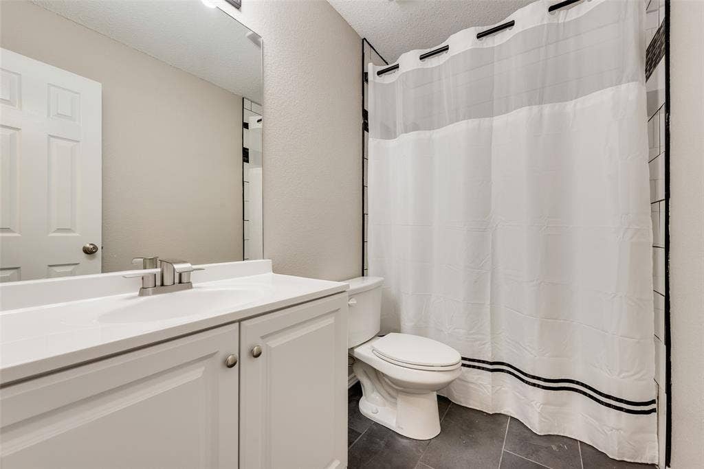 617 Madeline Court, Azle, TX 76020 Bathroom featuring a shower with shower curtain, vanity, dark tile patterned flooring, and a textured ceiling