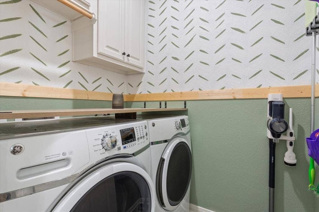 518 Alamo Court, McGregor, TX 76657 Laundry area featuring washing machine and clothes dryer, cabinet space, and a textured wall