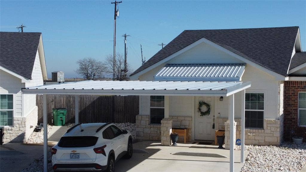518 Alamo Court, McGregor, TX 76657 View of front of house featuring stone siding, a metal roof, a standing seam roof, and a shingled roof