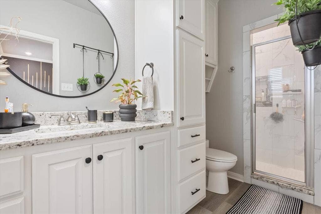 518 Alamo Court, McGregor, TX 76657 Bathroom with vanity, a shower stall, and dark wood finished floors