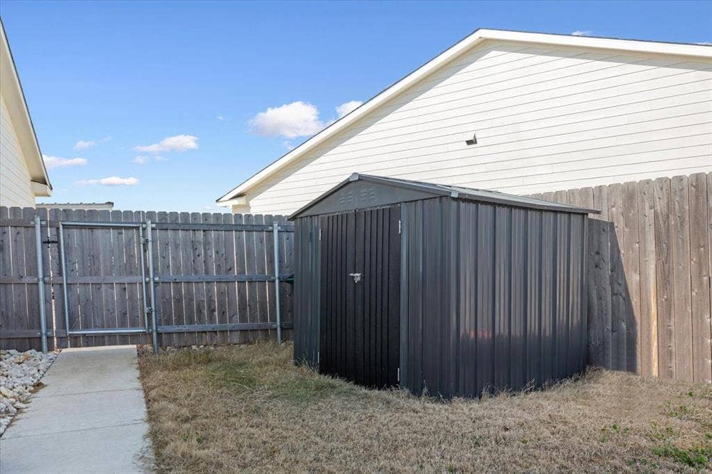 518 Alamo Court, McGregor, TX 76657 Fenced backyard with a shed and a gate