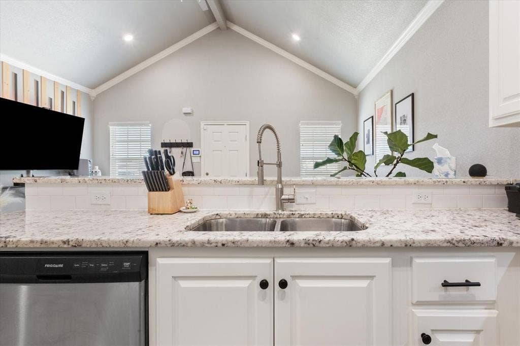 518 Alamo Court, McGregor, TX 76657 Kitchen with dishwasher, light stone counters, white cabinetry, open floor plan, and ornamental molding