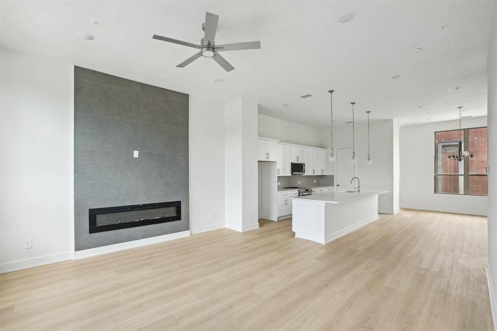 2524 Havenhurst Street, #102, Farmers Branch, TX 75234 Unfurnished living room with a large fireplace, light wood-type flooring, a ceiling fan, and a chandelier