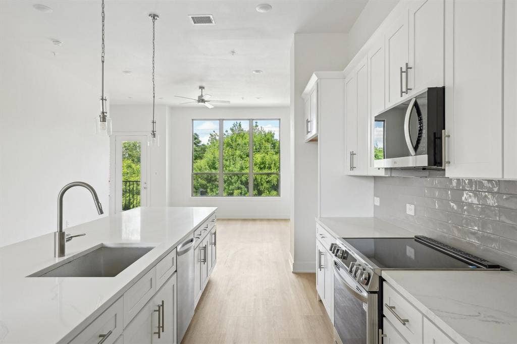 2524 Havenhurst Street, #102, Farmers Branch, TX 75234 Kitchen with appliances with stainless steel finishes, hanging light fixtures, white cabinetry, light wood-style floors, and light stone counters