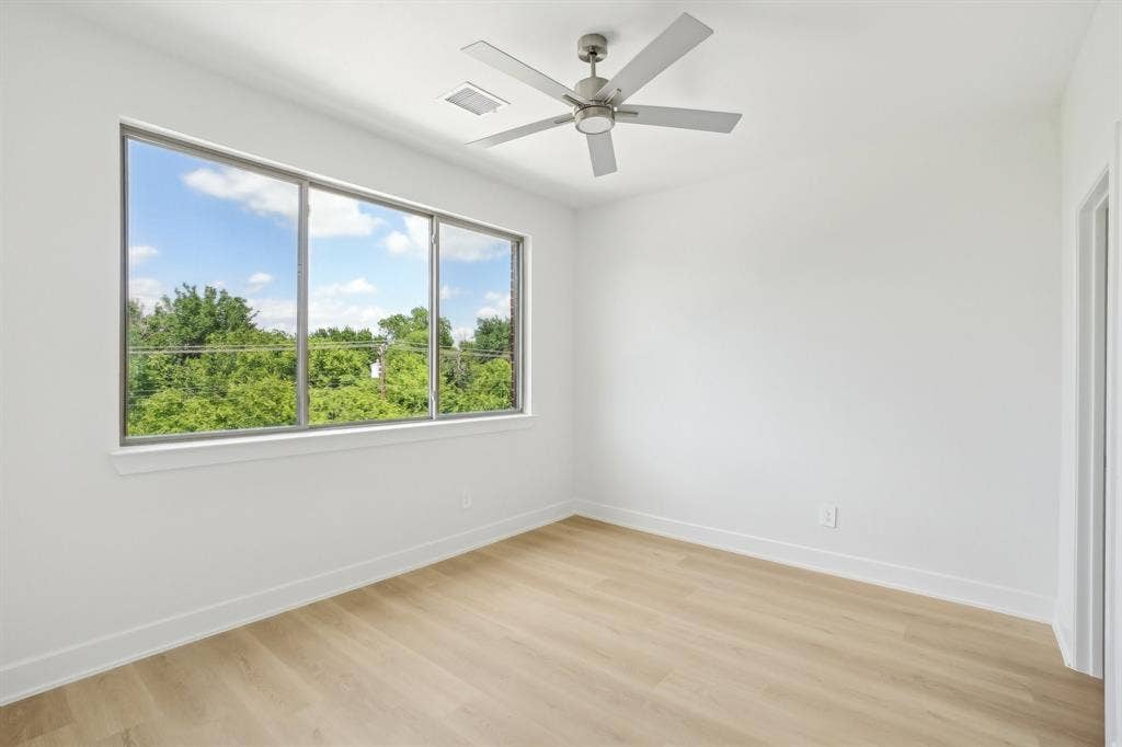 2524 Havenhurst Street, #102, Farmers Branch, TX 75234 Unfurnished room featuring light wood-style flooring, a ceiling fan, and view of scattered trees