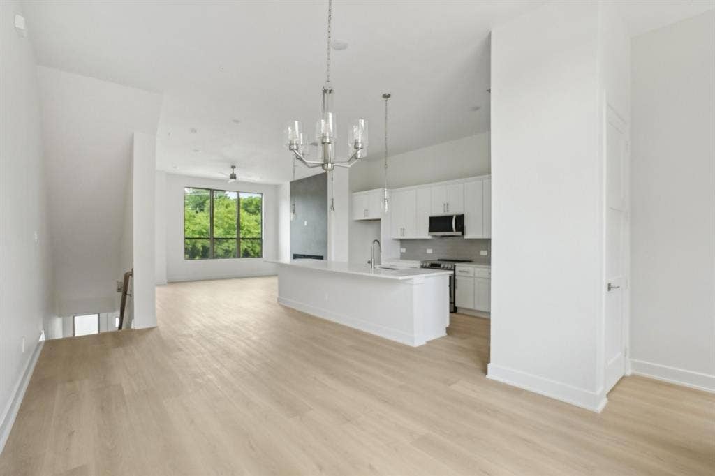 2524 Havenhurst Street, #102, Farmers Branch, TX 75234 Kitchen with open floor plan, white cabinets, a center island with sink, pendant lighting, and a chandelier
