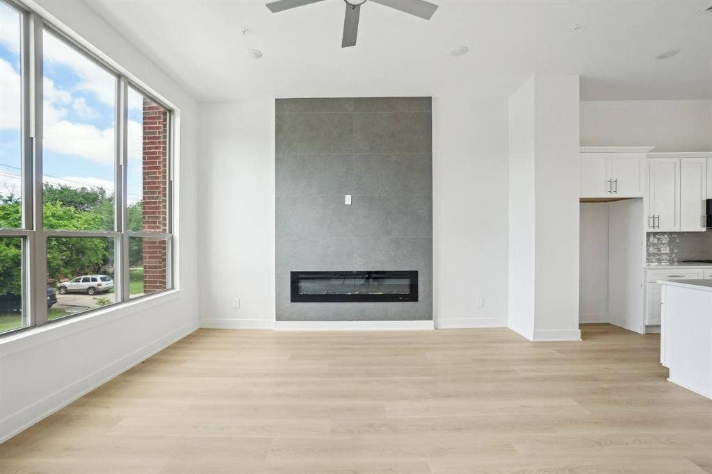 2524 Havenhurst Street, #102, Farmers Branch, TX 75234 Unfurnished living room featuring light wood finished floors, a large fireplace, and ceiling fan