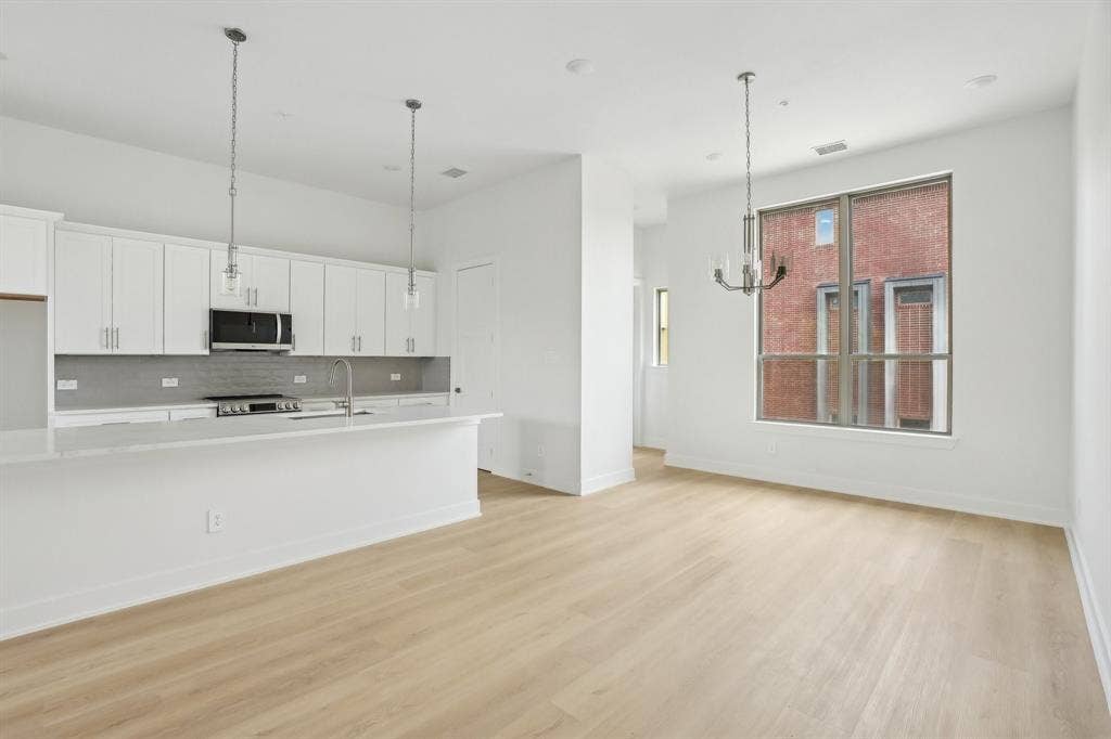 2524 Havenhurst Street, #102, Farmers Branch, TX 75234 Kitchen with white cabinetry, decorative light fixtures, light wood-style floors, appliances with stainless steel finishes, and backsplash