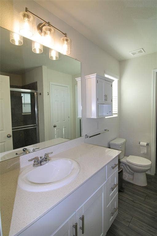 Full bath featuring vanity, a shower stall, and wood tiled floors