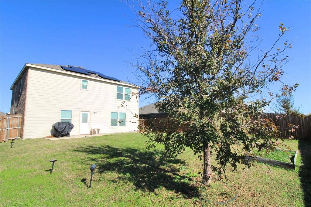Back of property featuring a fenced backyard and solar panels