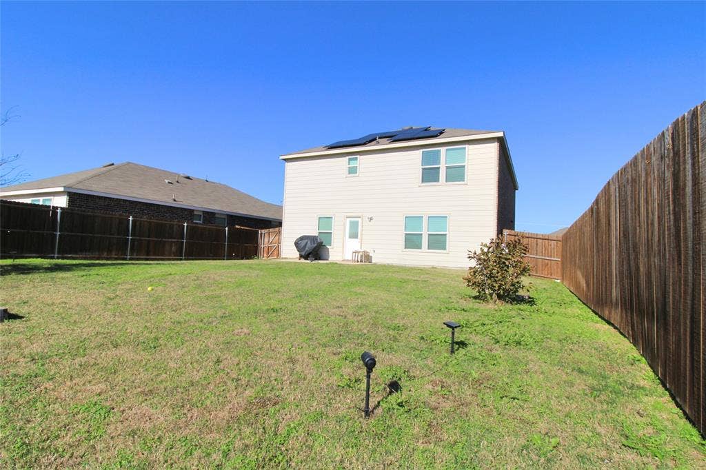 Rear view of house featuring a fenced backyard and roof mounted solar panels
