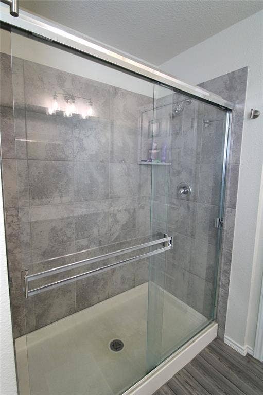 Bathroom featuring a shower stall, wood finished floors, and a textured ceiling