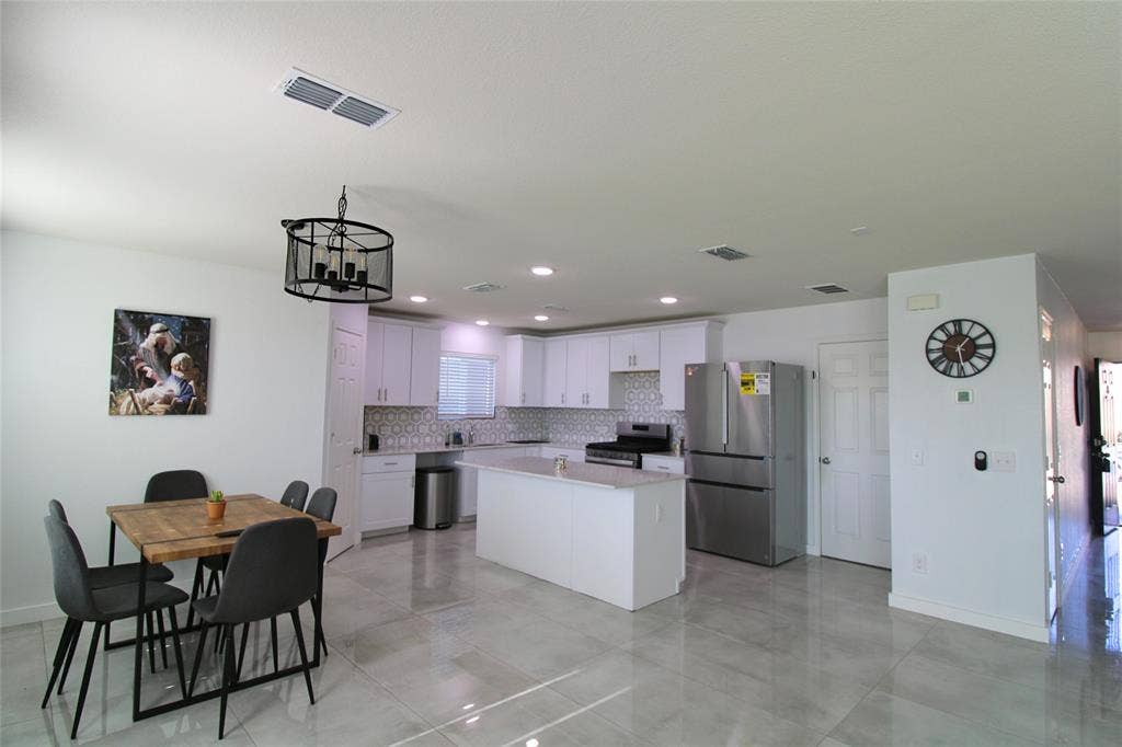 Kitchen with stainless steel appliances, white cabinetry, a center island, backsplash, and recessed lighting