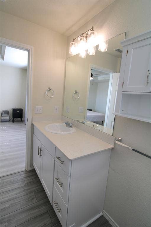Bathroom with vanity, dark wood-style floors, a ceiling fan, and ensuite bath