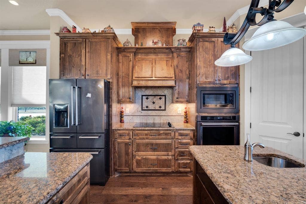 217 Hunter Pass, Waxahachie, TX 75165 Kitchen with black appliances, backsplash, light stone counters, dark wood-style floors, and crown molding