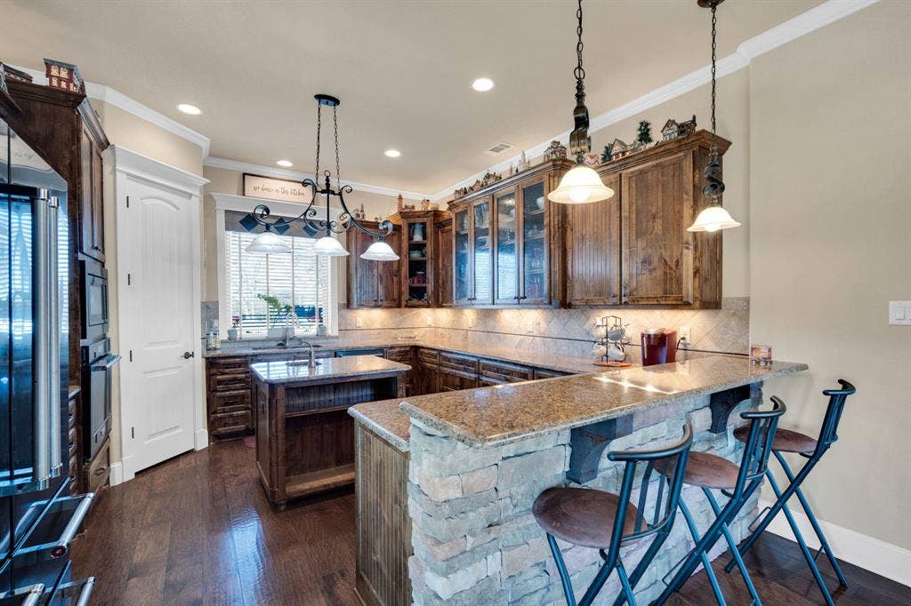 217 Hunter Pass, Waxahachie, TX 75165 Kitchen featuring a breakfast bar area, a kitchen island, pendant lighting, crown molding, and light stone countertops