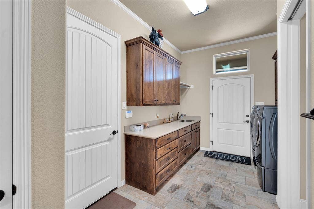 217 Hunter Pass, Waxahachie, TX 75165 Laundry room with ornamental molding, stone finish floors, independent washer and dryer, and cabinet space