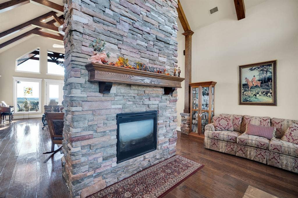 217 Hunter Pass, Waxahachie, TX 75165 Living room with beamed ceiling, high vaulted ceiling, a stone fireplace, and dark wood-type flooring