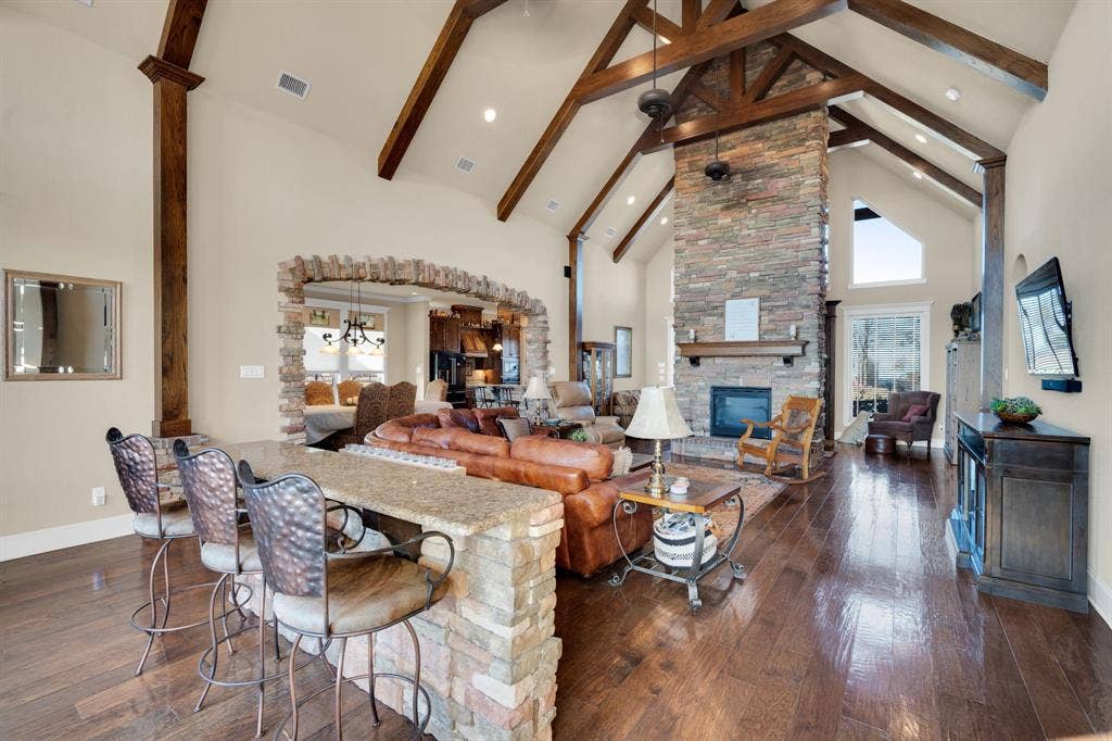 217 Hunter Pass, Waxahachie, TX 75165 Living area featuring high vaulted ceiling, a stone fireplace, dark wood-style floors, a chandelier, and healthy amount of natural light