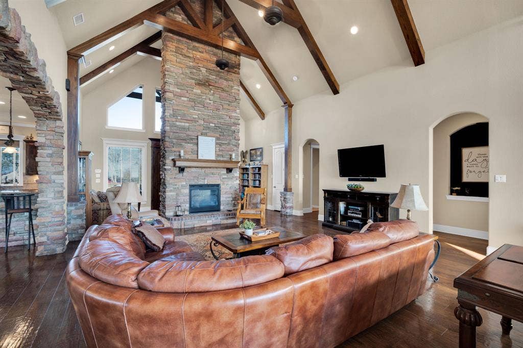 217 Hunter Pass, Waxahachie, TX 75165 Living area with high vaulted ceiling, arched walkways, a stone fireplace, dark wood-type flooring, and recessed lighting