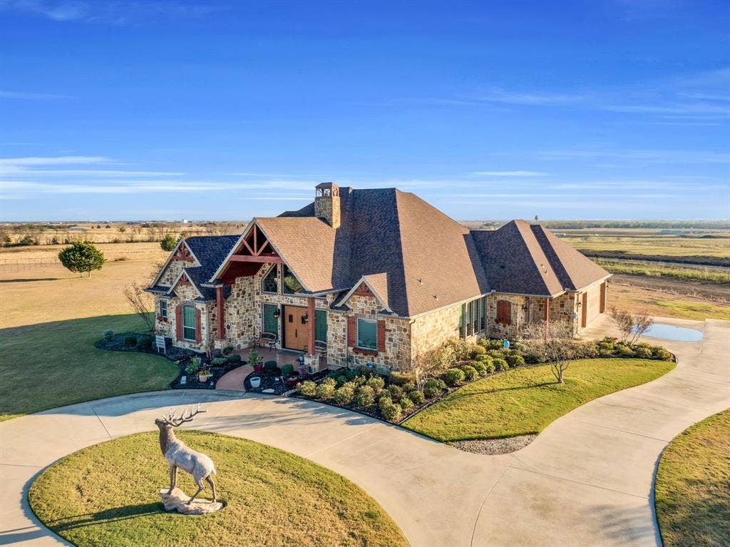 217 Hunter Pass, Waxahachie, TX 75165 View of front of house with stone siding, curved driveway, a front lawn, and a chimney
