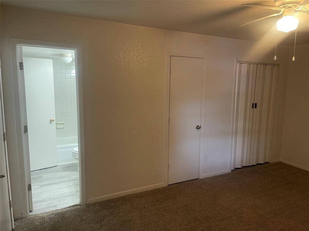 322 S Waco Street, Weatherford, TX 76086 Unfurnished bedroom with carpet flooring, ceiling fan, and ensuite bathroom