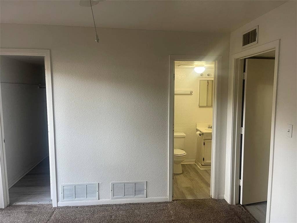 322 S Waco Street, Weatherford, TX 76086 Unfurnished bedroom with ensuite bath and carpet flooring