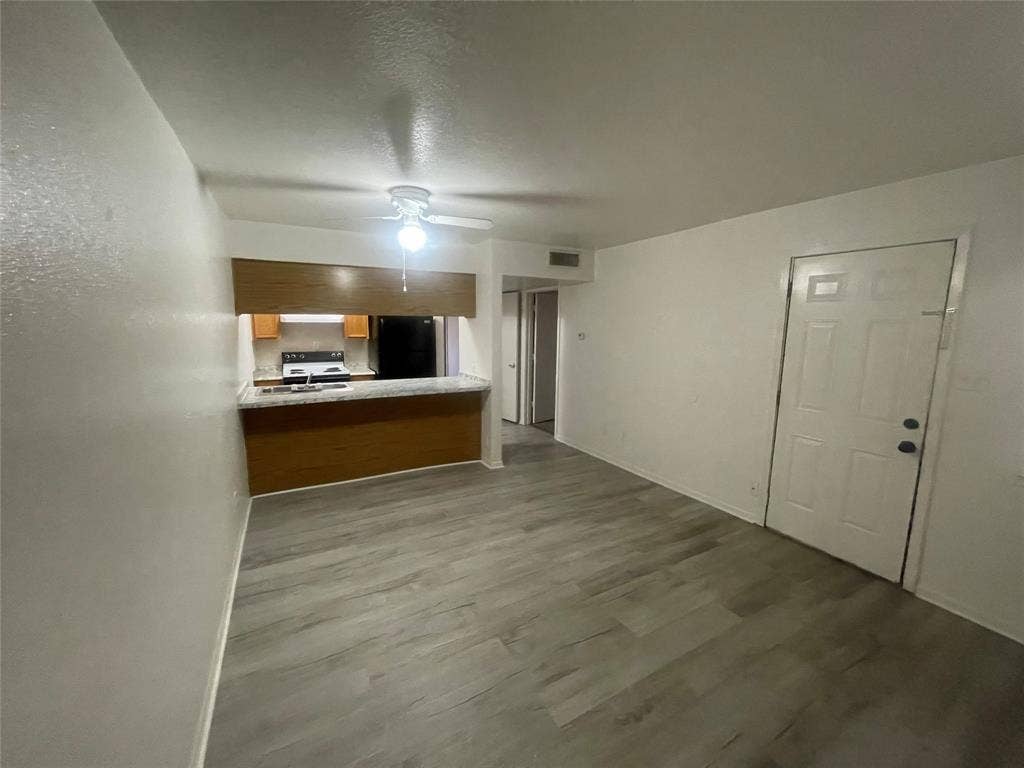 322 S Waco Street, Weatherford, TX 76086 Unfurnished living room featuring dark wood-style flooring, a ceiling fan, and a textured ceiling
